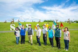 黄市長と徐処長などのゲストたちが官田ビジターセンターの大草原で集合写真を撮る